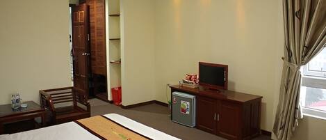A hotel room with a bed, a desk, a television, and a wardrobe.
