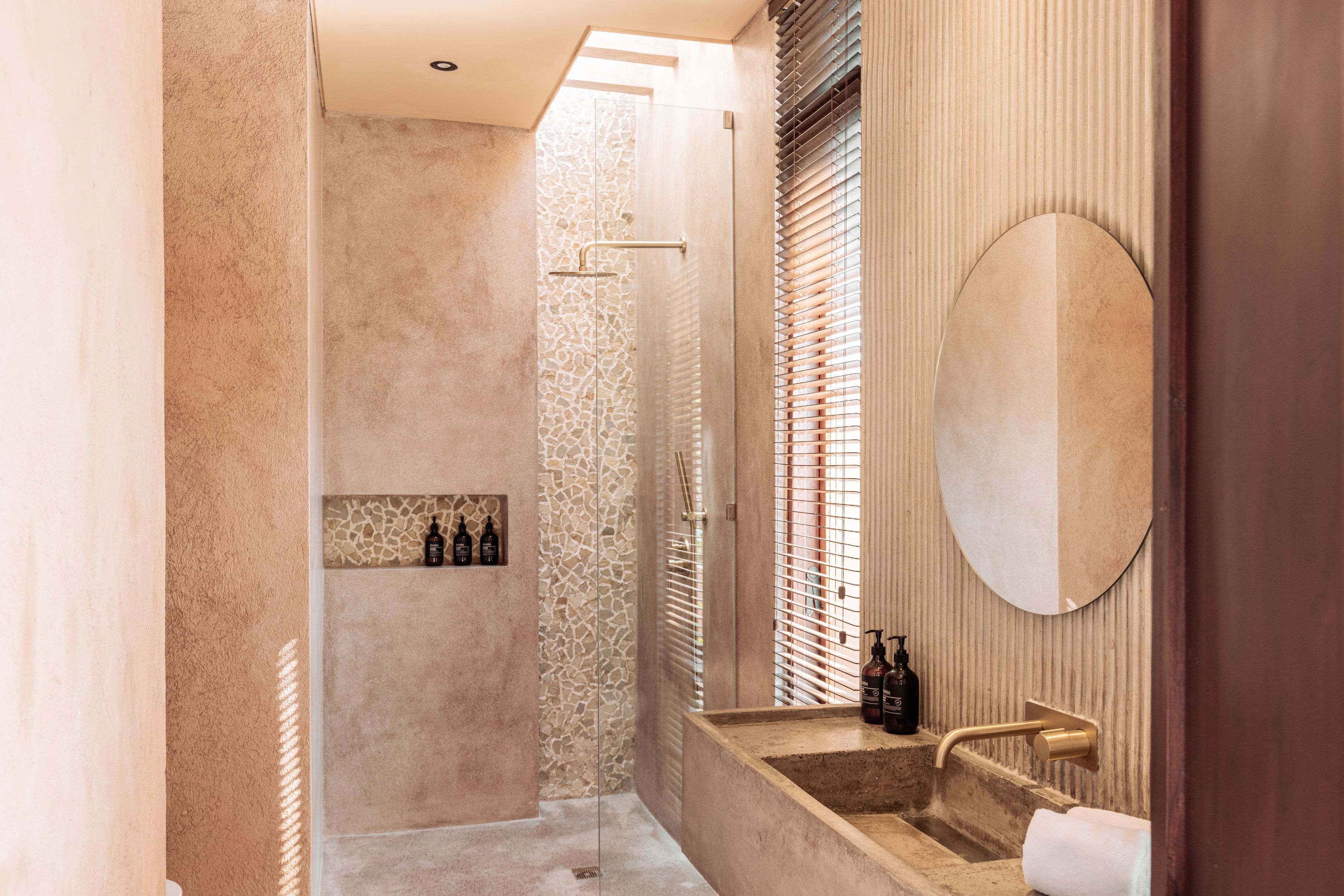 Un baño moderno con ducha de piedra, un espejo grande y un tocador con lavamanos.