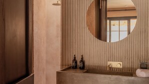 Een badkamer met een houten wastafelmeubel, een ronde spiegel en een handdoekhouder.