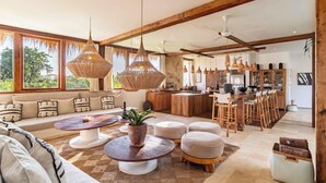 A spacious living area with a large sofa, round coffee tables, and a kitchen in the background.