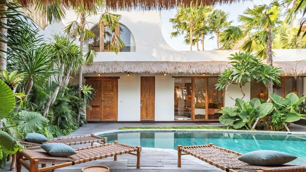 A poolside area with lounge chairs and a thatched-roof structure.