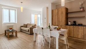 Een moderne woonkamer met een bank, een eettafel met stoelen, een keuken met houten kastjes en een radiator.