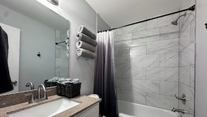Ein Badezimmer mit Waschbecken, Spiegel, Toilette und Dusche.