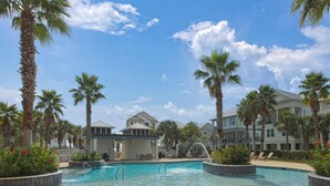 A swimming pool surrounded by palm trees and a building with a covered patio area. - Sea You Later by Kaiser Vacation Rentals Cottages at Romar 15 (Orange Beach)