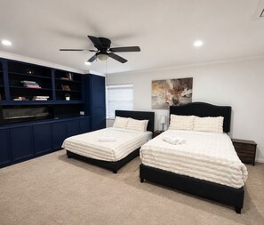 A bedroom with two beds, a ceiling fan, a bookshelf, and a painting on the wall. - Modern Houston Home nr Med Center & NRG - Pool, Wi‑Fi, Parking, Family‑Friendly (Houston)