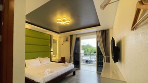 A modern hotel room with a large bed, a green accent wall, a balcony with a view, and a ceiling light fixture. - Dream'Star Resort Puerto Galera powered by Cocotel (Puerto Galera)