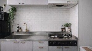 Una cocina moderna con armarios grises, un lavamanos de acero inoxidable, una estufa a gas y un horno empotrado.