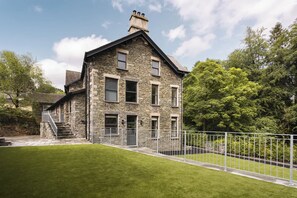 A stone building with a steep gabled roof, multiple windows, and a well-maintained lawn. - Riverside Summary:<br>Ri (Westmorland and Furness)