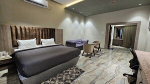 Een moderne hotelkamer met een groot bed, een bank, een klein tafeltje en een bureau.