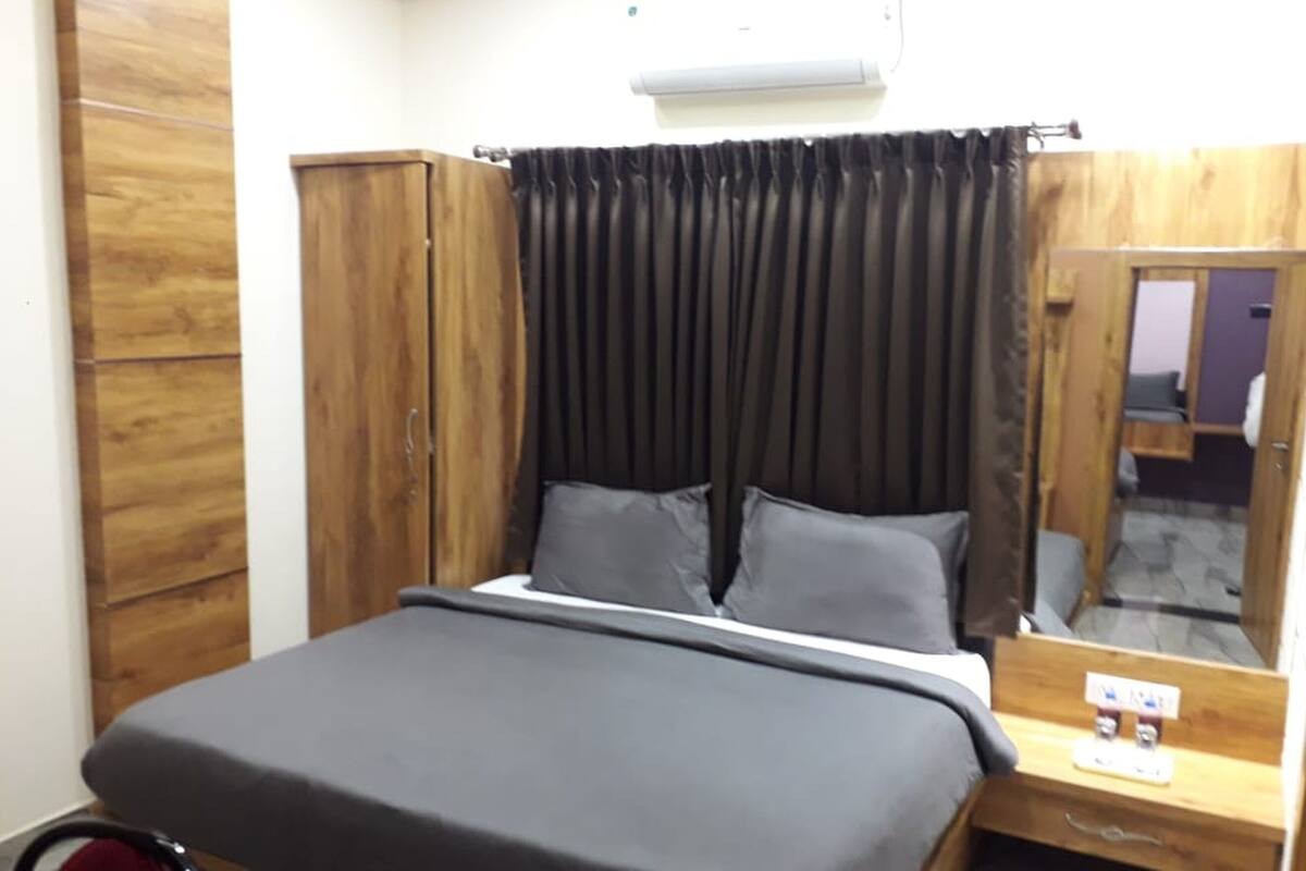 Een slaapkamer met een bed, een houten garderobe en een spiegel.