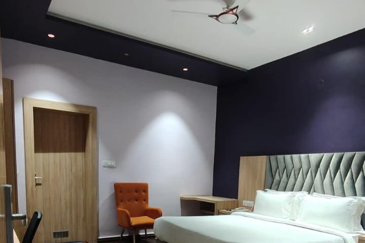 A modern bedroom with a bed, a chair, a desk, and a ceiling fan.