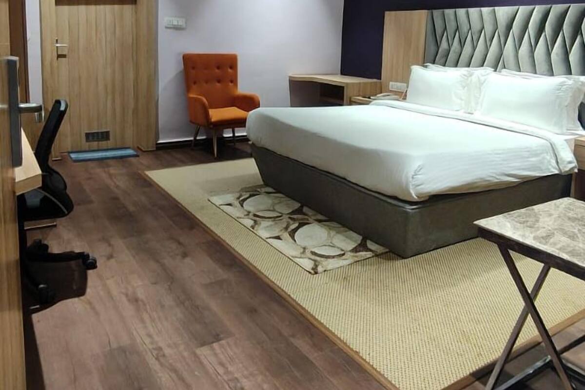 Een moderne slaapkamer met een bed, een stoel, een bureau en een plafondventilator.