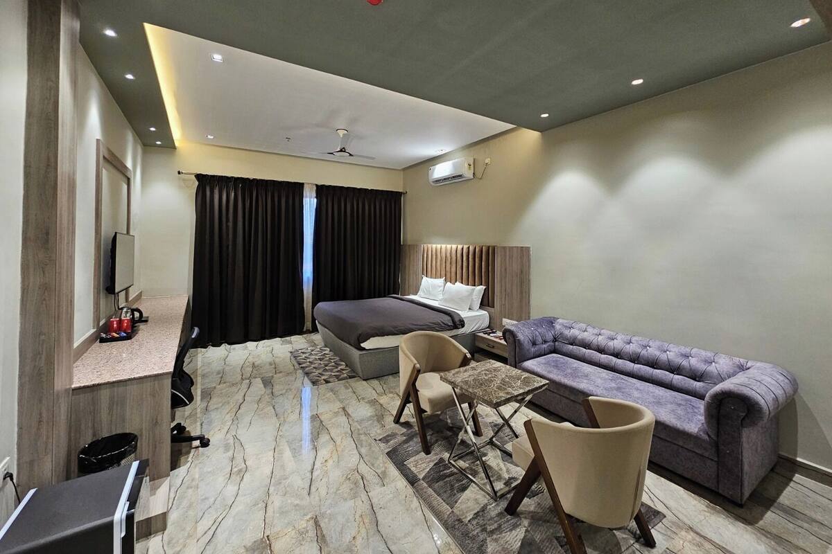 Een moderne hotelkamer met een bed, een bank, een bureau en een televisie.