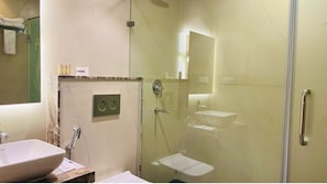 Baño con lavamanos de mármol, ducha con cerramiento de vidrio y barra de apoyo.