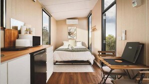 A compact bedroom with a bed, bedside table, and a desk with a chair. - Hollow Mountain Getaway 1 by Tiny Away (Laharum)