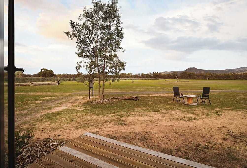 Une terrasse extérieure avec une plateforme en bois, deux chaises et une table.