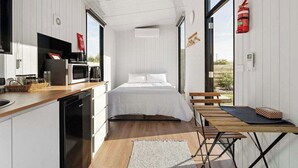A compact room with a bed, a small kitchen area, and a dining table. - Rosebrook Riverviews by Tiny Away (Rosebrook)