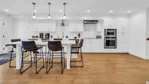 A modern kitchen with white cabinetry, a central island, and pendant lighting.