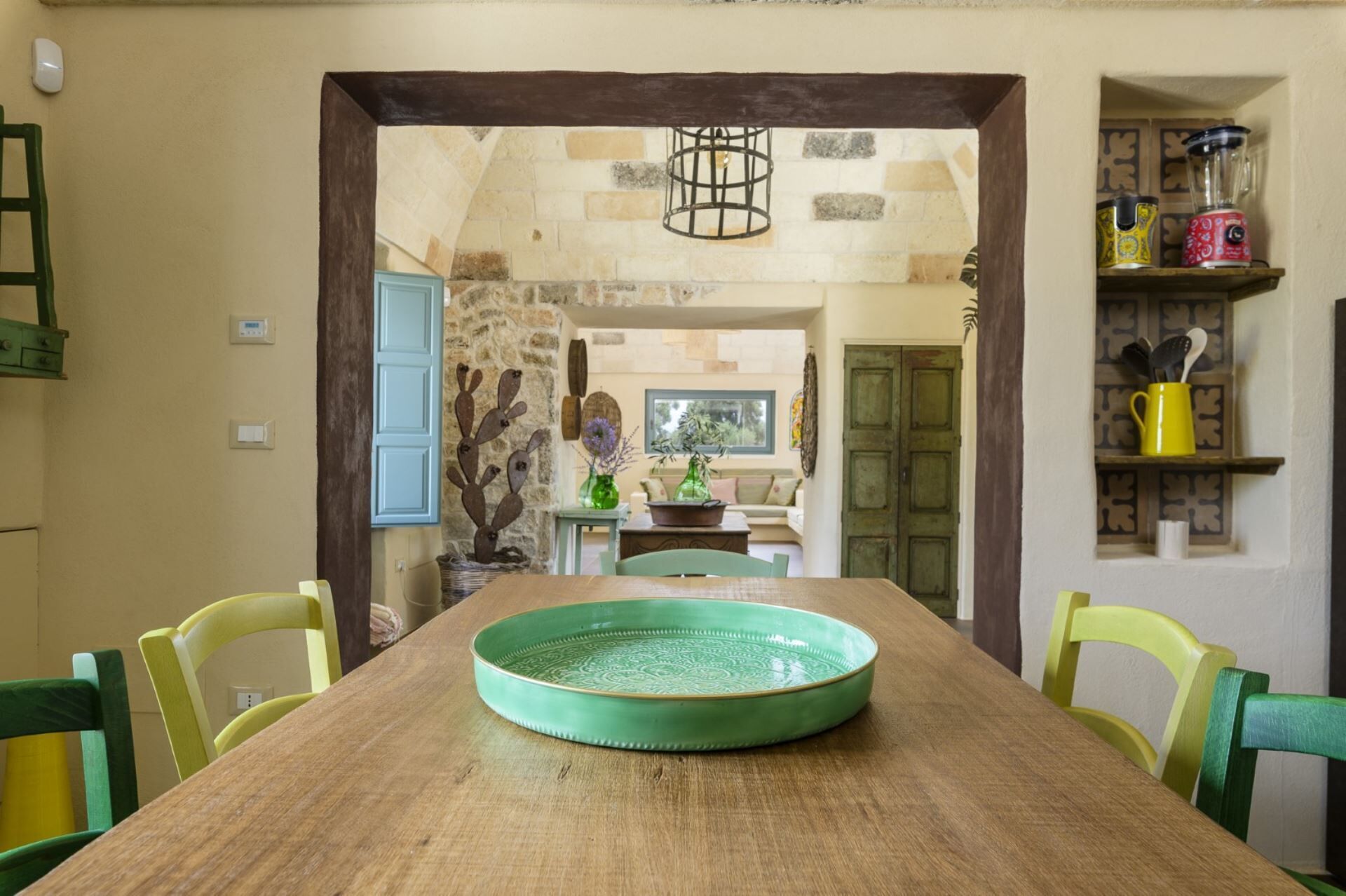 Un comedor con mesa de madera, sillas y un plato decorativo verde.