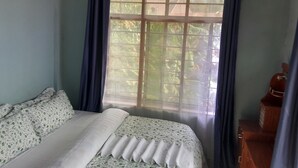 A room with a bed, a window with curtains, and a wooden cabinet. - HIGHLAND BREEZE AVACADO HOTEL (Mbeya)