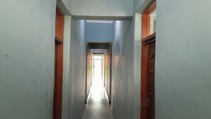 A narrow, well-lit hallway with a door at the end leading to a brighter area. - HIGHLAND BREEZE AVACADO HOTEL (Mbeya)