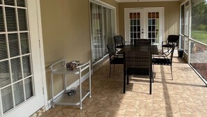 Un patio techado con una mesa de comedor y sillas, un ventilador de techo y ventanas grandes.