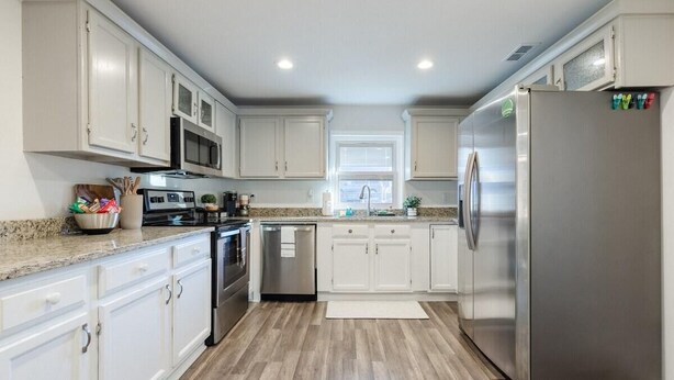 A modern kitchen with white cabinets, stainless steel appliances, and a granite countertop.