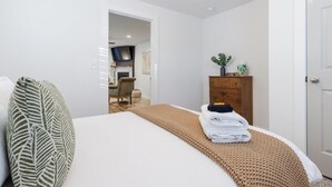 A hotel room with a bed, a wooden dresser, and a door.