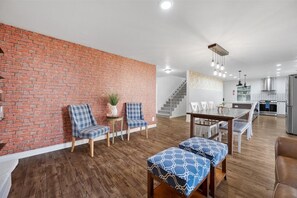 Red brick accent wall with sitting area and the kitchen beyond - Secret Garden | 8BR•Game Room•Fire Pit & Waffles! (Orem)