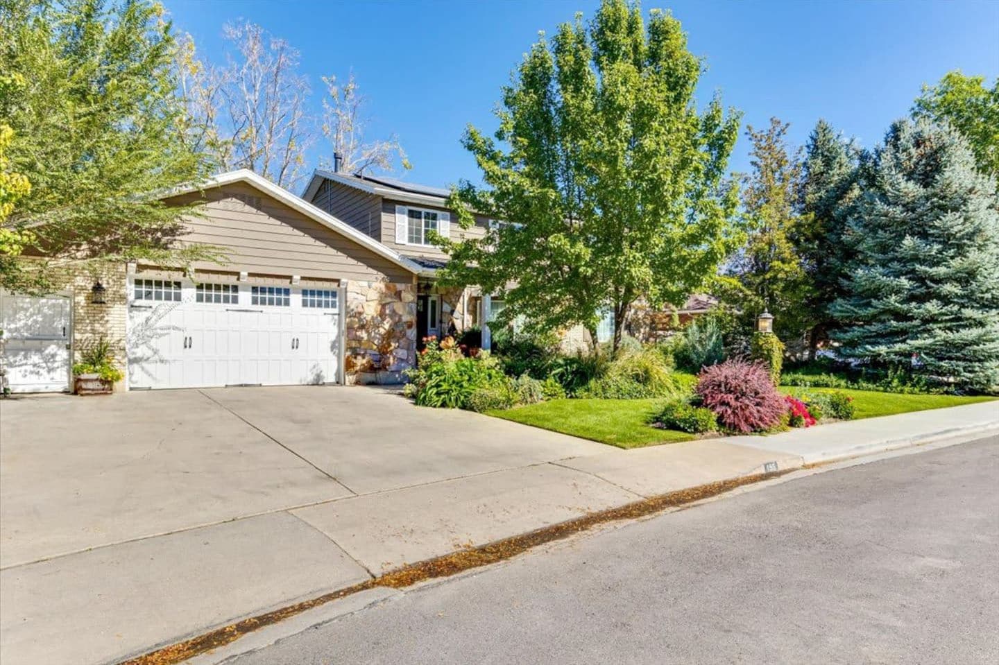 Front of the home with a two-car garage and mature trees