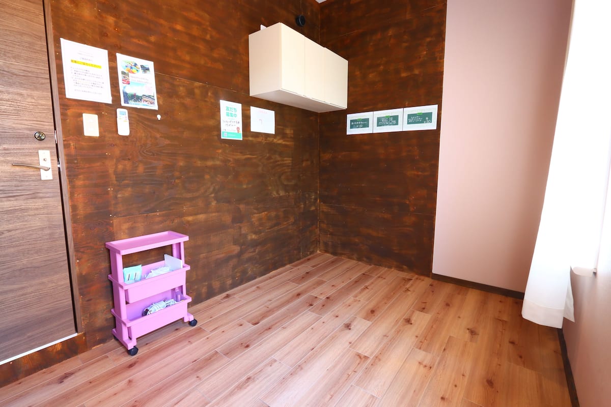 A room with wooden flooring, a pink storage cart, and several informational signs on the walls.