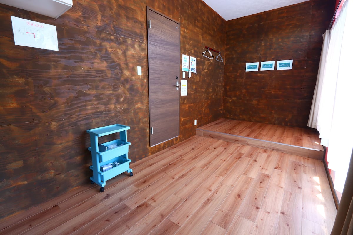 A room with wooden flooring, a blue cart, a door, and three signs on the wall.