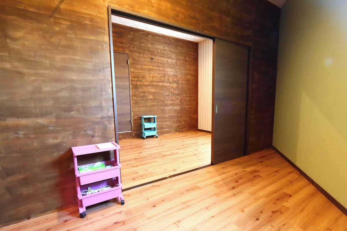 A room with wooden flooring, a sliding door, and a pink storage unit.