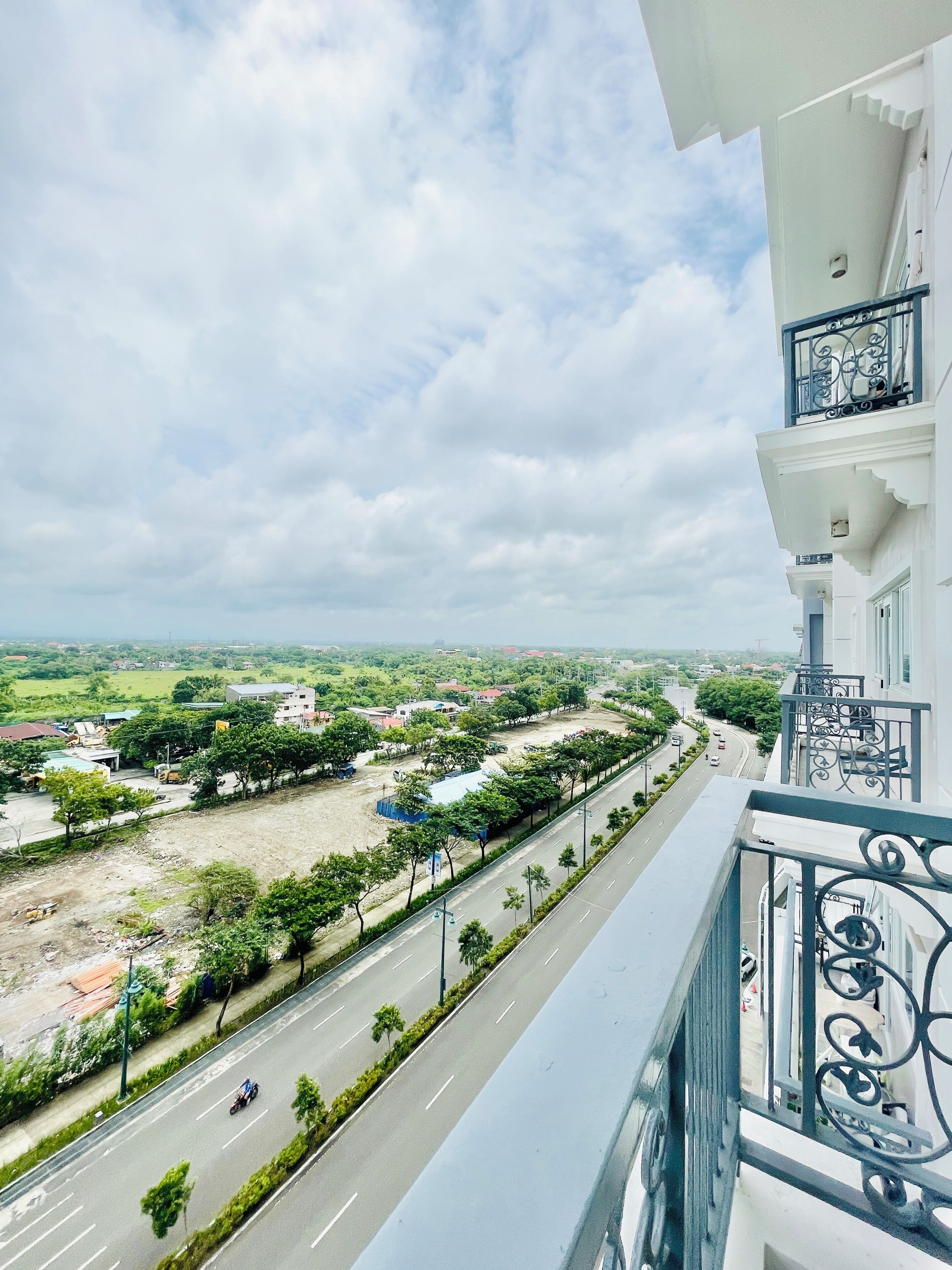 A balcony with a view of a road and surrounding buildings.