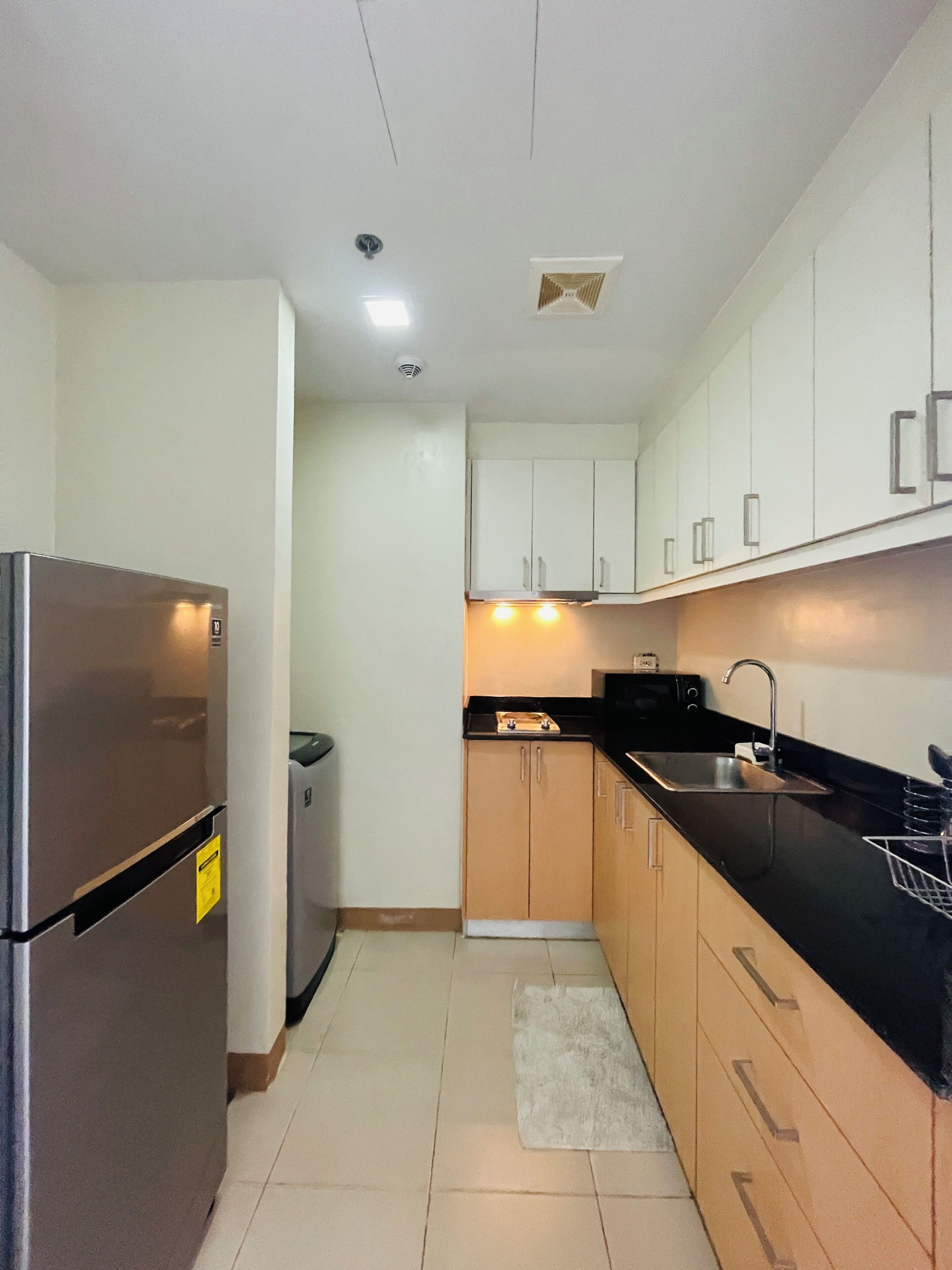 A compact kitchen with a refrigerator, sink, and cabinets.