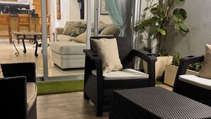 Ein modernes Wohnzimmer mit Korbmöbeln, einer Glastür, die in eine Küche führt, und einem Topf mit einer Pflanze.