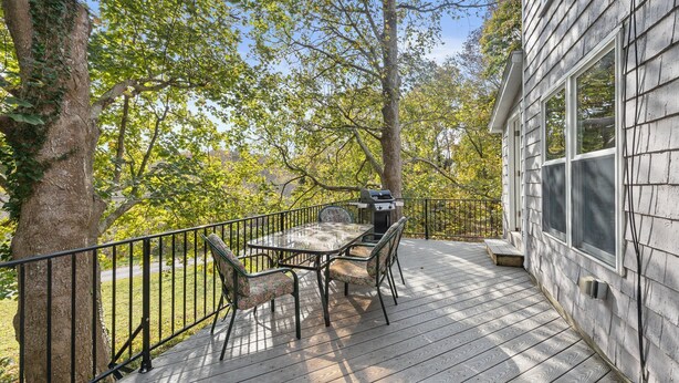 Une terrasse avec une table et des chaises, un barbecue et une maison avec une fenêtre.