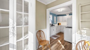 Une cuisine spacieuse avec des meubles blancs, une chaise en bois et un tapis sur le sol.