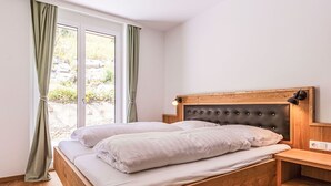 A bedroom with a wooden bed, a nightstand, and a window with curtains. - Lovely apartment for 4 guests with WIFI, TV, terrace and panoramic view (Brandstätter)