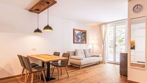 A modern living room with a wooden dining table, two chairs, a sofa, and a lamp. - Lovely apartment for 4 guests with WIFI, TV, terrace and panoramic view (Brandstätter)