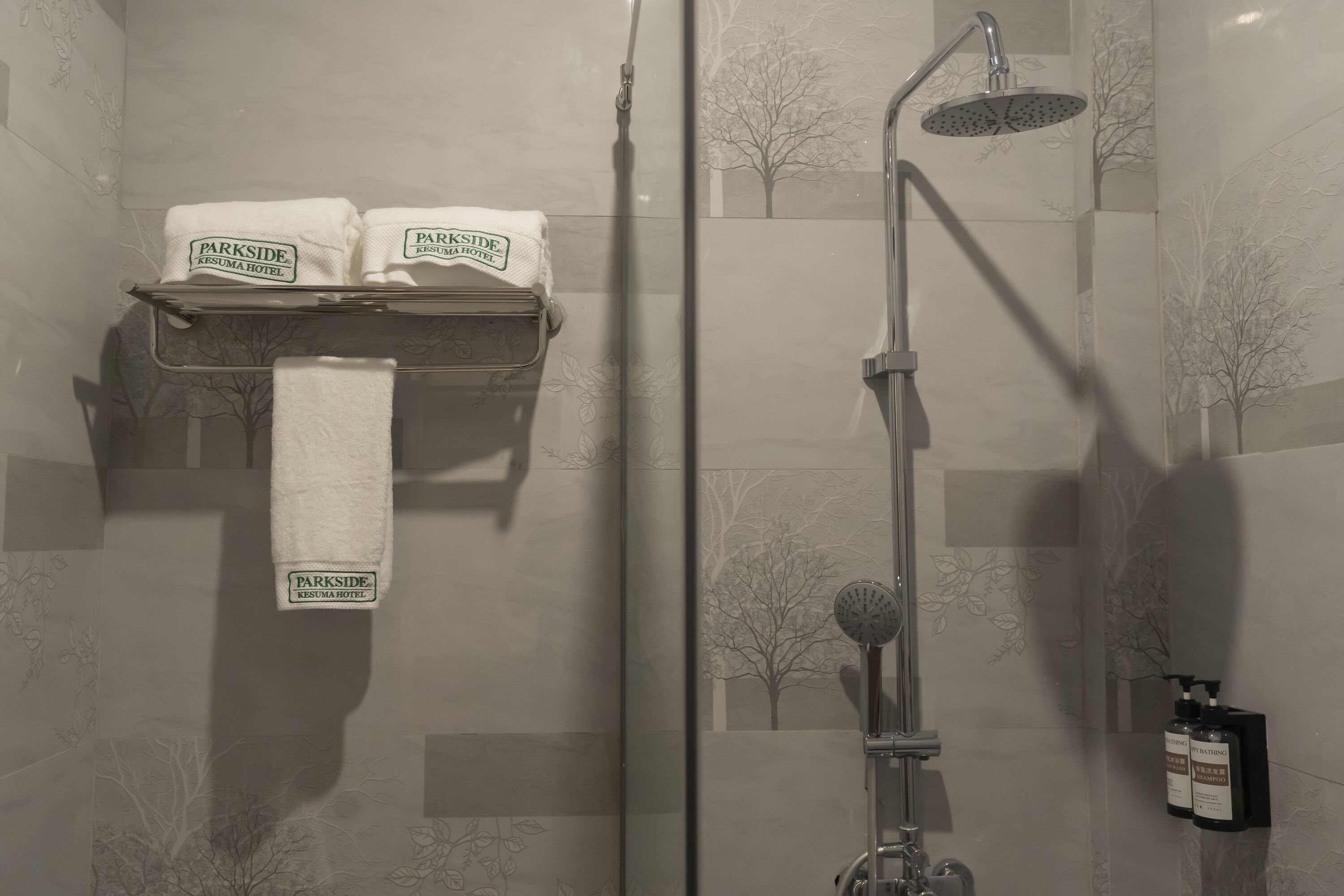 A shower area with a towel rack holding two towels and a showerhead.