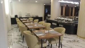 A restaurant with marble flooring, multiple tables with chairs, and a buffet area. - Parkside's Hotel Palembang (Palembang)