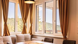 A modern dining area with a wooden table, cushioned seating, and large windows with curtains. - Nice apartment for 4 people with WIFI, TV, terrace and panoramic view (Brandstätter)