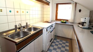 Una cocina compacta con un lavamanos doble, estufa y cafetera.