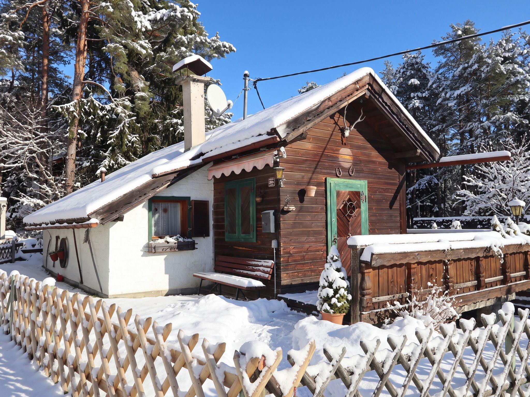 Une cabane en bois avec un toit en pente, une véranda à l’avant et une cour clôturée.