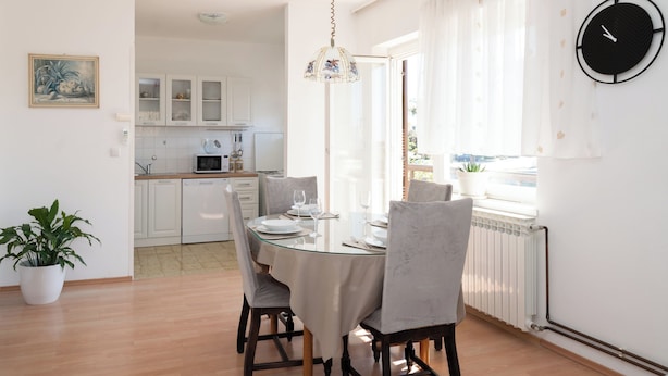 A dining area with a glass table, chairs, and a hanging light fixture. - Spacious 2 Bedroom Apartment With Balcony (Sibenik)