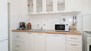 A modern kitchen with white cabinets, a stainless steel sink, a microwave, and a coffee maker. - Spacious 2 Bedroom Apartment With Balcony (Sibenik)