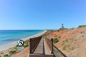 A wooden boardwalk leading to a beach with clear skies.