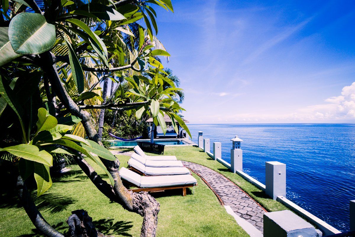 A poolside area with lounge chairs, a pathway, and a view of the ocean.