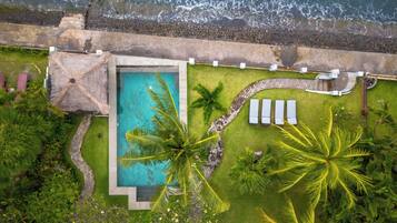 Luftaufnahme eines Resorts mit Schwimmbad, Palmen und Strand.